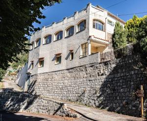a building on a stone wall next to a street at le gite du vial in Revest-les-Roches