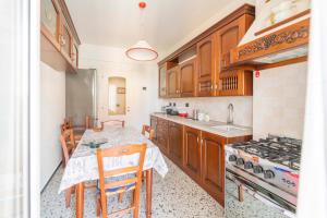 a kitchen with wooden cabinets and a table with chairs at 193 - Casa Via della Chiusa - centralissimo e vicino alla baia del silenzio, spiaggia e mare 150m - Parcheggio GRATIS incluso e Aria condizionata in Sestri Levante