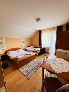 ein Hotelzimmer mit 2 Betten und einem Tisch in der Unterkunft Kelemen Vendégház 2 in Praid