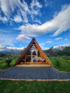 a frame house with a window on a grass field at Glamping El Muelle in Villa de Leyva