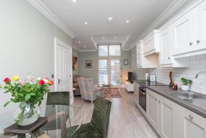 a kitchen with white cabinets and a glass table with flowers at 5 Star - The Ulsterville Residences - Free On-site Parking in Belfast
