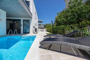 a swimming pool with two chairs next to a house at Luxury Villa Adria Apartments in Krk