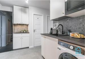 a kitchen with white cabinets and a sink at Bigly Room in Gdańsk