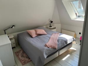 a bedroom with a bed with two pink pillows at Villa Brigitta, havsnära boende mittemot Klostret i Ystad centrum in Ystad