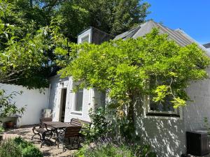 una pequeña casa blanca con una mesa y una mesa de picnic en Villa Brigitta, havsnära boende mittemot Klostret i Ystad centrum, en Ystad