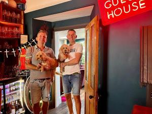 Dois homens estão numa loja a segurar um cão. em Brightham House em Salcombe