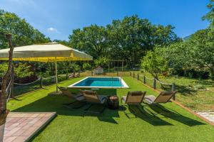 a swimming pool with chairs and an umbrella at PLAVAC in Kostelj