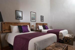 um quarto com 2 camas com lençóis roxos e brancos em Casa Brunella - Hotel Boutique Querétaro em Querétaro