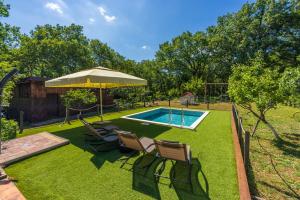 a backyard with a pool and chairs and an umbrella at PLAVAC in Kostelj