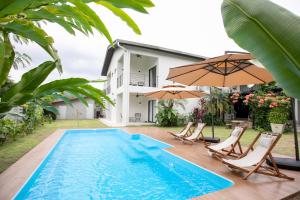 a swimming pool with chairs and umbrellas next to a house at Kontor Mansion - 3 mins to Teluk Chempedak Beach & Private Pool in Kuantan