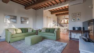 a living room with two green chairs and a table at Villa Fraiano in Palaia