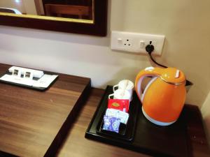 Keswani Group Tashi Heritage Hotel & Resort في جانجتوك: طاولة غرفة الفندق مع غلاية شاي برتقال عليها