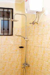 a shower in a bathroom with a yellow tiled wall at Keisha Luxury Furnished Apartment Bukoto in Kampala