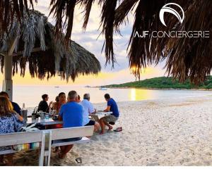 un groupe de personnes assises à des tables sur une plage dans l'établissement Appart'hotel grande terrasse vue mer, à Ajaccio