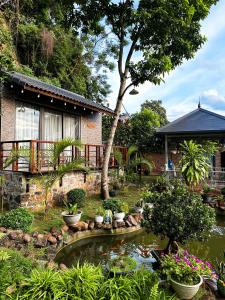 a garden with a pond in front of a house at Gobies Garden in Mộc Châu