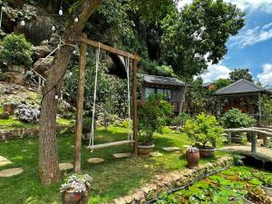 een tuin met een schommel en een vijver bij Gobies Garden in Mộc Châu