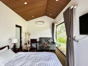 1 dormitorio con cama, sofá y TV en Gobies Garden en Mộc Châu