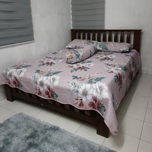 kak yatt homestay serendah في سيرينداه: سرير عليه بطانية وردية ومخدات
