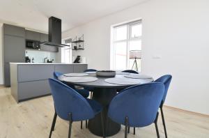 a kitchen and dining room with a table and blue chairs at LL Properties - G7 Luxury House By The Harbor in Akureyri