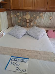 a bed with two pillows on top of it at Caravana Villa Rosa in Málaga