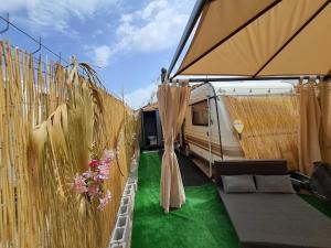 a camper with a tent and a couch and grass at Caravana Villa Rosa in Málaga