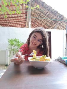 Une fille assise à une table avec un bol de nourriture dans l'établissement The Amora, à Baie d'Arugam