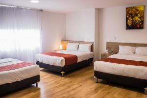 um quarto de hotel com duas camas e uma janela em Nogal Suite Hotel Ipiales em Ipiales