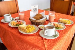 a table topped with plates of food and cups of coffee at Nogal Suite Hotel Ipiales in Ipiales