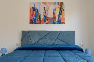 a bedroom with a blue bed with a painting on the wall at Piazza Pio Suite Home in Rome