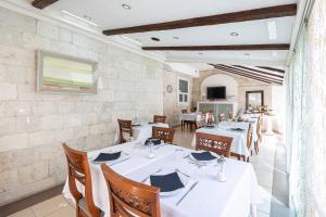 una sala da pranzo con tavoli bianchi e sedie in legno di Heritage Hotel Vila Sikaa a Trogir