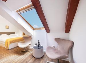 sypialnia na poddaszu z łóżkiem i 2 krzesłami w obiekcie Heritage Hotel Vila Sikaa w Trogirze