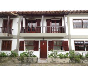 Casa blanca con puerta roja y ventanas en Lindo Apartamento em Cabo Frio, en Cabo Frío