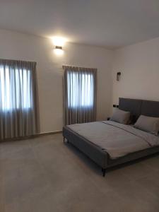 um quarto com uma cama grande e 2 janelas em בית דירות - בית אורן em Bet Sheʼan
