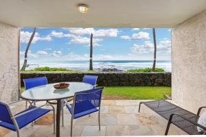un patio con mesa, sillas y el océano en Kona Reef A4, en Kailua-Kona