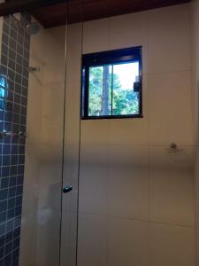 a bathroom with a shower and a window at Refúgio Allamanda Flats in Visconde De Maua
