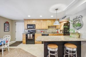 a kitchen with wooden cabinets and a island with bar stools at Cozy American Fork Retreat with Electric Fireplace in American Fork