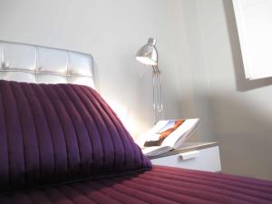 ein Schlafzimmer mit einem lila Bett mit einer Lampe und einem Buch in der Unterkunft Casa Rota By KubiK in Cáceres