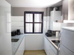 a kitchen with white cabinets and a window at Casa Rota By KubiK in Cáceres