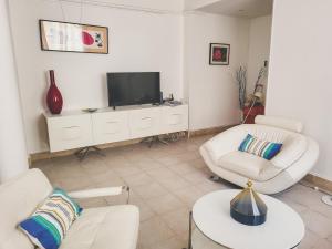 a living room with two white chairs and a tv at Le Pytheas Vieux Port Marseille in Marseille