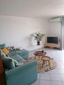 een woonkamer met een blauwe bank en een tafel bij Appart' cosy climatisé à 10' des plages et de Sète in Frontignan