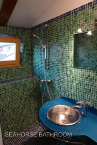 a green tiled bathroom with a sink and a shower at Vila Nada Piran in Piran