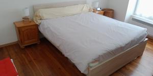 1 dormitorio con 1 cama con sábanas blancas y suelo de madera en L'Isard, en Pierrefitte-Nestalas