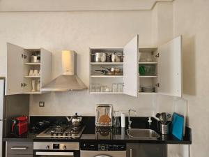 a kitchen with white cabinets and a stove top oven at Très bel appartement en face du parc, près du Novotel in Mohammedia