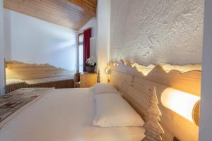 ein Schlafzimmer mit einem Bett mit einer Holzwand in der Unterkunft Hotel Cova in Pellizzano
