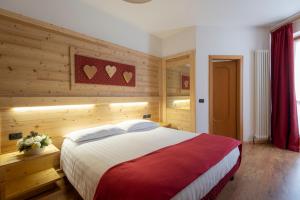 a bedroom with a large bed with wooden walls at Hotel Cova in Pellizzano