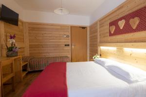 a bedroom with a large white bed and a desk at Hotel Cova in Pellizzano