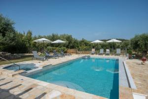 a large swimming pool with chairs and umbrellas at Villa Martha Perithia Corfu in Perítheia