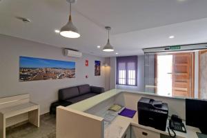 Apartamentos Antequera في أنتيكيرا: مكتب فيه مكتب وبه جهاز كمبيوتر وأريكة