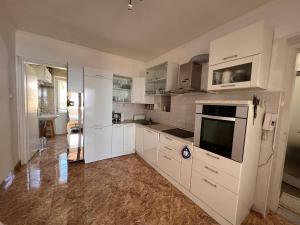 斯普利特的住宿－Adriatic View，白色的厨房配有白色的橱柜和电视