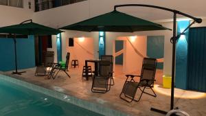 a swimming pool with chairs and tables and umbrellas at Hotel Las Brisas in Catemaco